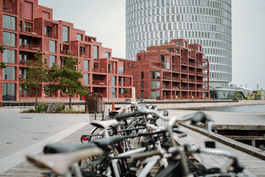 A row of parked bicycles with modern buildings in the background