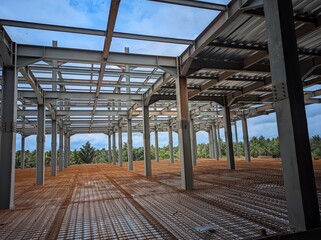 A large empty building with a lot of exposed beams. The building is unfinished and has a lot of empty space
