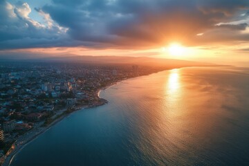 Fototapeta premium Aerial view of coastal city at sunset, golden hour light reflecting on the ocean.