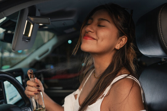 Woman applying perfume inside a car