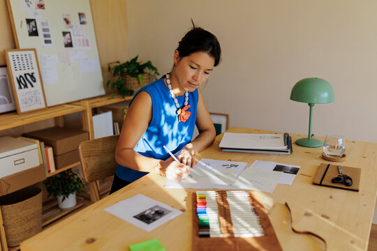 Female designer sketching new ideas using pencil and paper at desk