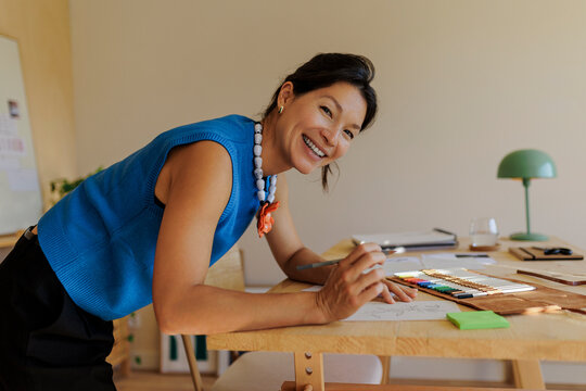 Happy creative woman drawing sketches in design studio