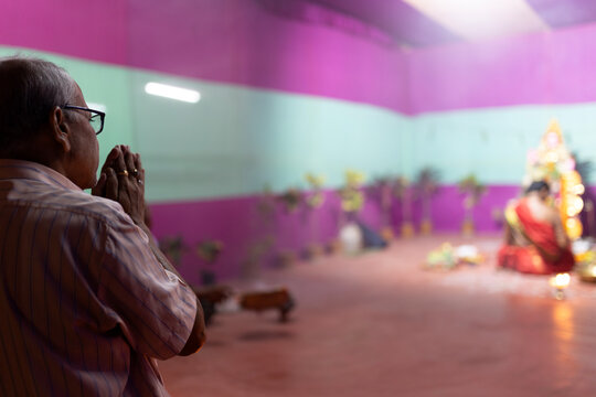 An aged man offering prayer to the Hindu Goddess