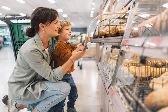Mother and son selecting fresh bread from the bakery section