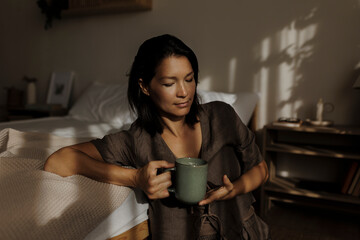 Woman enjoying a cup of coffee in her minimalist bedroom