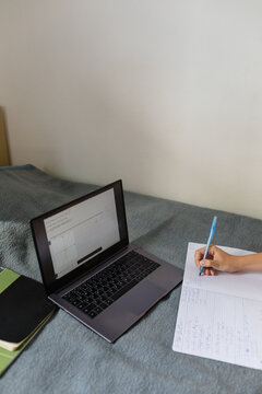 Student's computer and exercise book on the bed