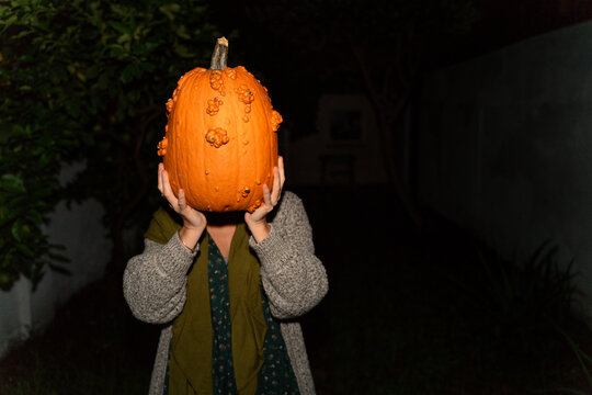 Person Holding Pumpkin at Night