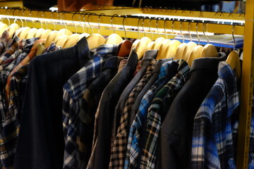 Thrifting's vibrant collection of sweaters, shirts, hoodies, trousers and knitted t-shirts are elegantly displayed on wooden hangers, featuring a variety of colors and textures.