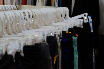 Thrifting's vibrant collection of sweaters, shirts, hoodies, trousers and knitted t-shirts are elegantly displayed on wooden hangers, featuring a variety of colors and textures.