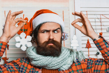 Serious Santa Claus bearded man in Christmas hat hold snowflakes decoration during celebration of...