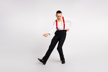 Young man in stylish retro attire showcasing energetic dance moves on white background