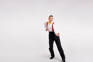 Young stylish male dancer on white background expressing elegance and joy with vibrant moves,...