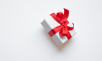 Simple white paper craft gift box with red ribbon bow in dynamic angle.anniversary and special day...