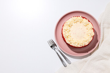 Red velvet cake on pink plate and towel on white background, space for text