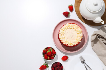 Red velvet cake on pink plate, towel, teapot and berries on white background, space for text
