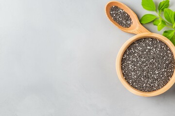 Wooden Bowl and Spoon with Chia Seeds on Light Background with Green Leaves