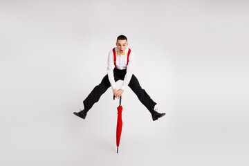 Energetic young man leaping in the air with a colorful umbrella on a white background