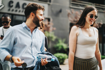 Smiling business people walking outdoors in a city environment, enjoying a casual conversation. The image captures a sense of teamwork, connection, and relaxation amidst urban life.