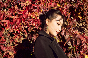 Asian woman taking photos by the river with red leaves in autumn