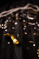 close up of gold ribbon with silver and gold confetti and beads in the background against a black fabric, celebration themed, New Year's Eve