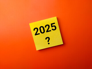Yellow sticky note with number 2025 and question mark symbol on a orange background. Business concept