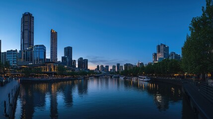 Obraz premium A panoramic view of a city skyline at dusk reflected in a calm river.