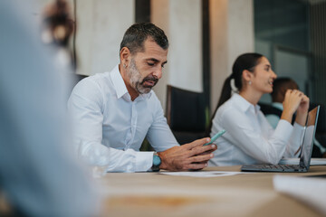 A multicultural business team is seen working collaboratively in a modern office environment, illustrating teamwork, communication, and technology use during a meeting.