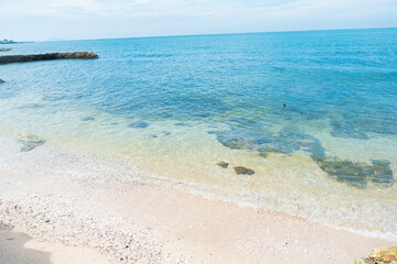 Soft blue ocean wave on clean sandy beach with rocks and splashing waves,Summer vibe on holiday vacation.