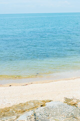 Soft blue ocean wave on clean sandy beach with rocks and splashing waves,Summer vibe on holiday vacation.