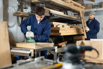 Man using electric planer on wooden plank at the workshop