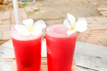 Watermelon smoothie with plumeria flowers, Fresh watermelon juice with ice in a glass,summer refreshing drink in glasses,Slices of watermelon on the table.