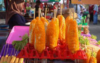 Freshly fried corn dogs displayed on a plastic tray at a night food festival. Street food corn dogs stuffed with cheese are sold at a food stand