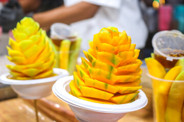 Display of mango slices in flower shape. or rujak, mango with spicy peanut sauce. Mango skewer in flower shape