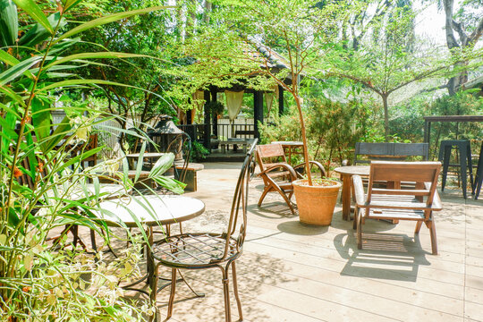 Wooden table and chair set in garden on a sunny day,outdoor seating for restaurant or cafe,Neat paved patio with sitting area and small garden in forest.