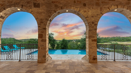Stunning sunset view from a luxurious stone terrace overlooking a pool