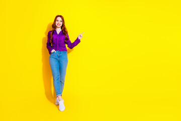 Full body length photo of red hair young woman in purple shirt and jeans advertising proposition isolated on yellow color background