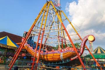 pirate ship or swinging boat in the amusement park in the afternoon. Rides the boat swing at the fun fair at night