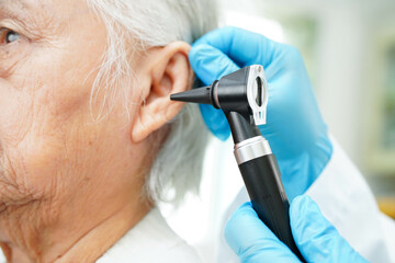 Otolaryngologist or ENT physician doctor examining senior patient ear with otoscope, hearing loss...