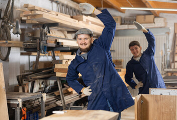 Two young male workers in carpentry workshop warm up while working ..