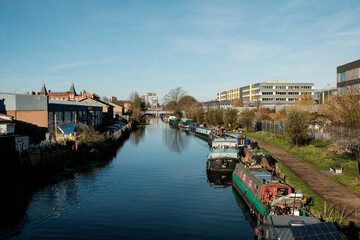 River lea reflecting modern buildings and canal boats in hackney wick, london