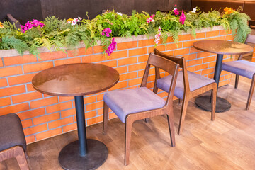 Wooden chairs and tables with green forest wall,flower and red brick wall in Relax restaurant or cafe.