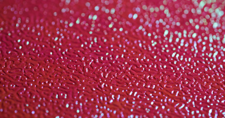 Blurred texture. Plastic sheet. Red patterned artificial leather relief with changing lighting. Decorative bright flare skin background.