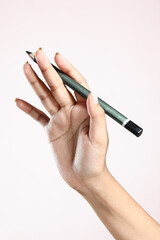 hand holding pencil on a plain background 