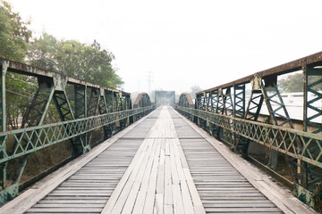 Old wooden Bridge with old railway ocated near street road and river.