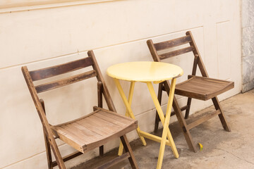 Yellow table and wooden chairs at cozy house or restaurant in garden,modern home decor,Contemporary interior design of dining space,minimal concept.