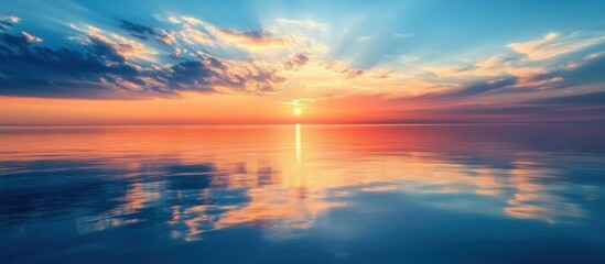 Calm sea water reflecting the sky with clouds and sunset.