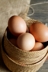 Fresh brown eggs nestled in a rustic wicker basket. The eggs have a warm, golden hue and appear to be organic.