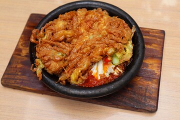 Crispy omelet complete with spicy chili sauce on a black plate in close view on the table.