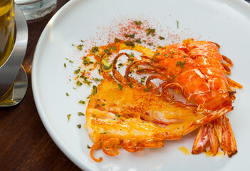 Appetizing cut in half grilled shrimps served on white plate..
