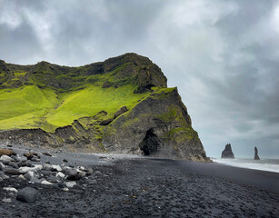 Reynisfjara black-sand beach features a cave, basalt columns and the Reynisdrangar sea stacks. 